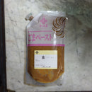 A pouch of Japanese golden sesame paste with a pink and white label, placed on a white marble countertop.